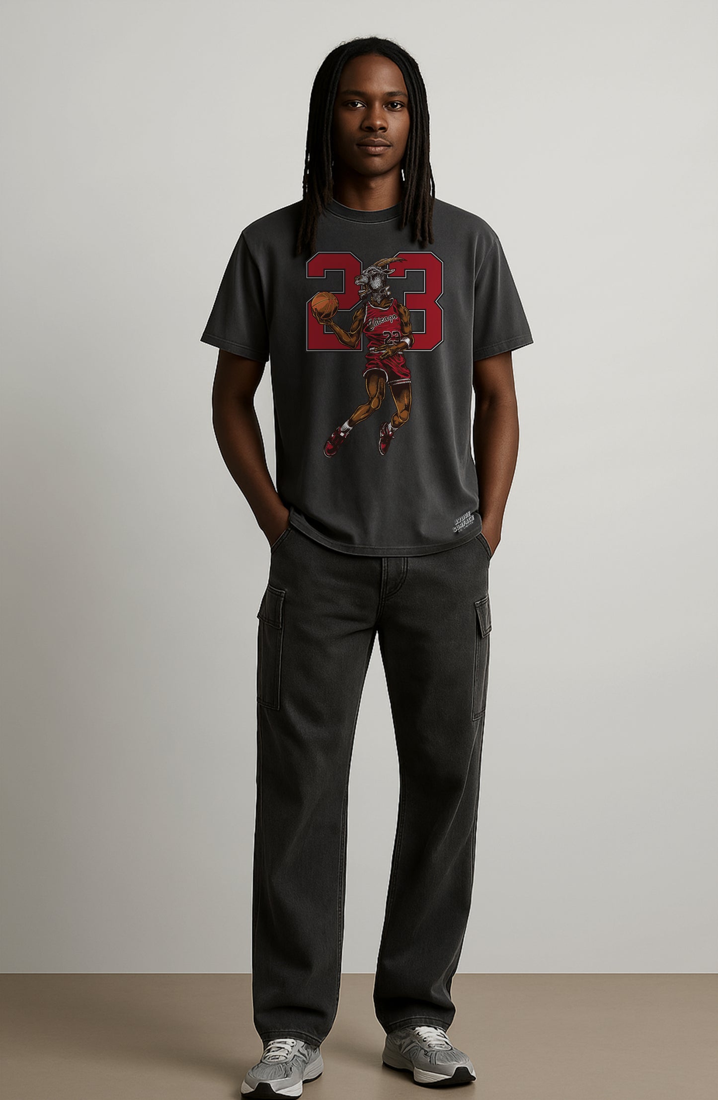 Person wearing a gray t-shirt with a graphic design on a plain background