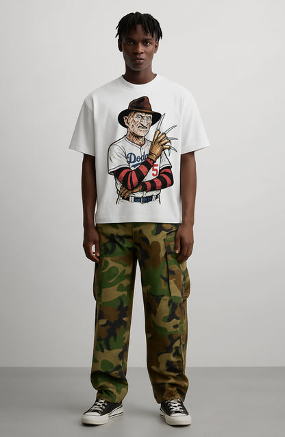 Person wearing a white t-shirt with a graphic design and camouflage pants on a plain background
